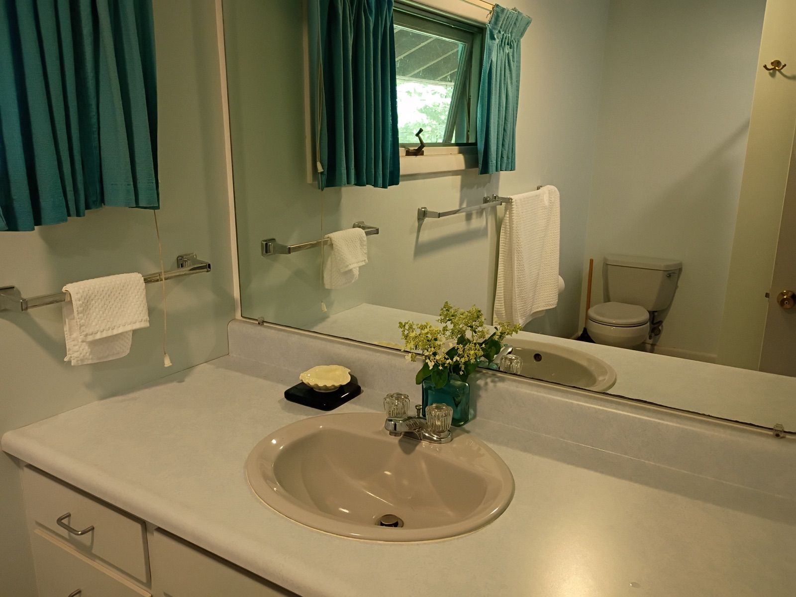 Clean bathroom vanity, sink, mirror, and folded towels